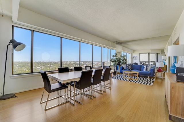 dining space with visible vents, baseboards, a textured ceiling, and light wood finished floors