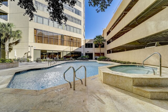 community pool with a patio area and a hot tub