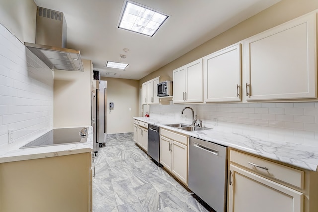 kitchen featuring light stone counters, island range hood, a sink, appliances with stainless steel finishes, and backsplash