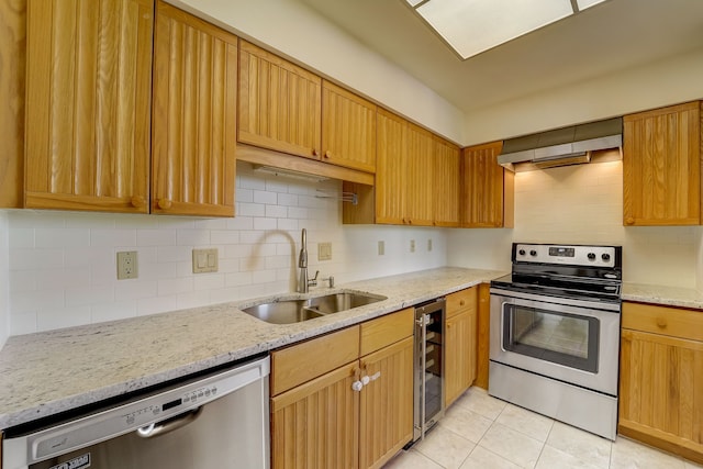 kitchen with wine cooler, light stone counters, extractor fan, stainless steel appliances, and a sink