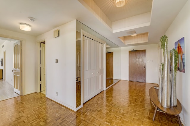 hallway featuring a raised ceiling, visible vents, and baseboards