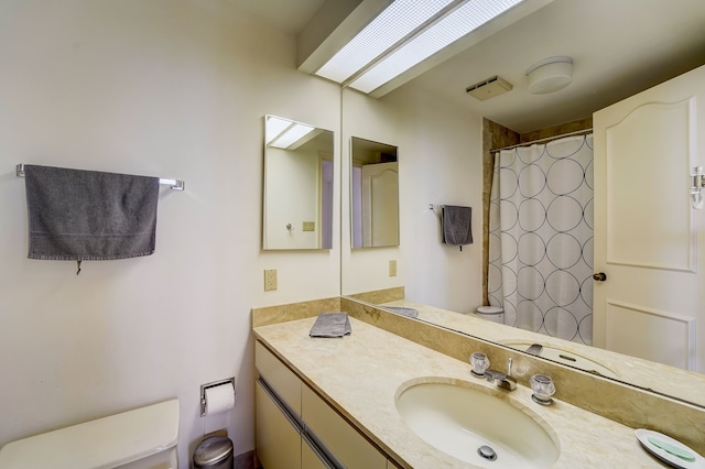 full bath featuring toilet, curtained shower, and vanity