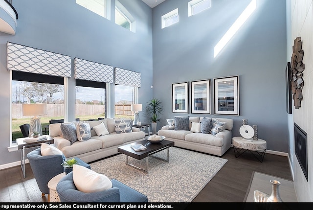 living room with dark hardwood / wood-style floors, a healthy amount of sunlight, and a towering ceiling