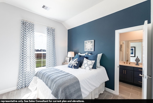 bedroom featuring vaulted ceiling, light colored carpet, sink, and ensuite bath