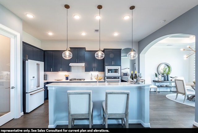 kitchen with stainless steel appliances, hanging light fixtures, and dark wood-type flooring