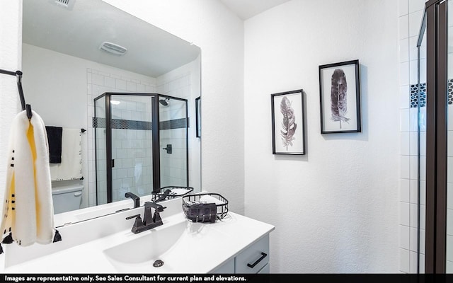 bathroom with vanity, toilet, and a shower with shower door