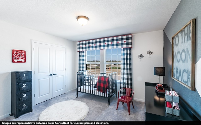 bedroom with a nursery area, a closet, carpet floors, and a textured ceiling