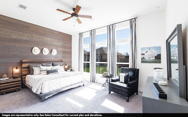 bedroom with wood walls, carpet, and ceiling fan