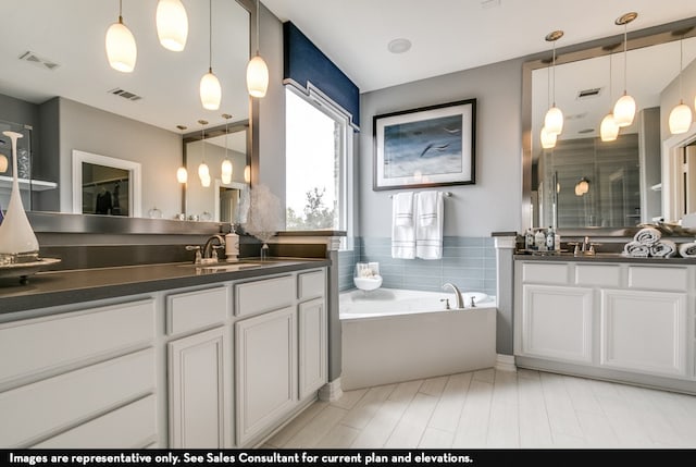 bathroom featuring tile patterned flooring, a bath, and double sink vanity