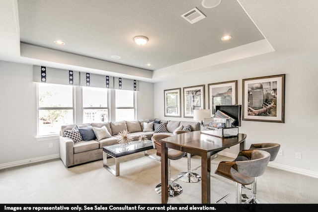 living room with light carpet, a tray ceiling, and a textured ceiling