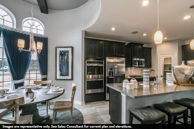 kitchen with appliances with stainless steel finishes, decorative light fixtures, sink, a kitchen bar, and an inviting chandelier