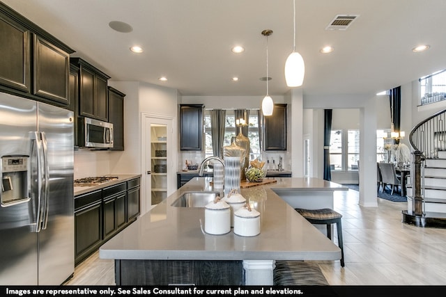 kitchen featuring appliances with stainless steel finishes, sink, pendant lighting, dark brown cabinetry, and a spacious island