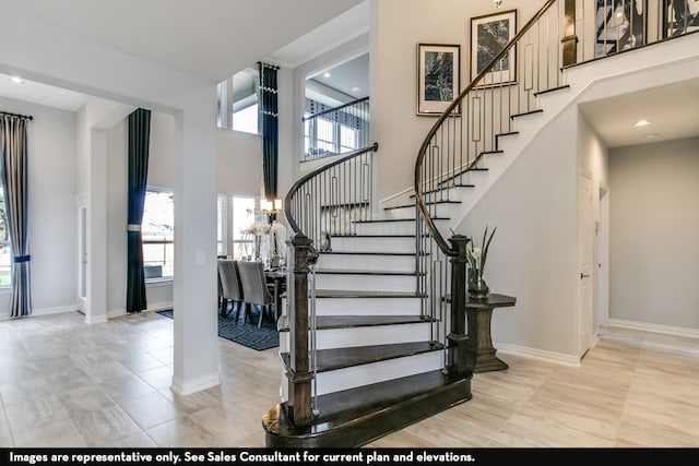 stairs with a towering ceiling and light tile patterned floors