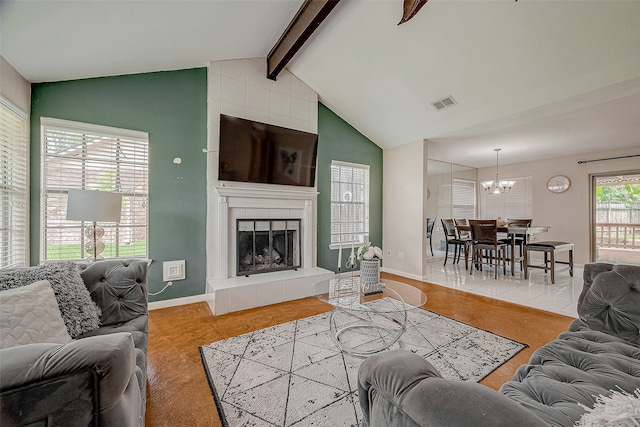 tiled living room featuring vaulted ceiling with beams, a tiled fireplace, and a notable chandelier