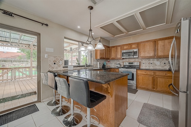 kitchen featuring decorative backsplash, a breakfast bar area, appliances with stainless steel finishes, and light tile patterned floors