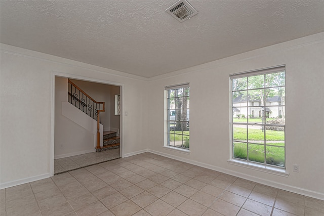 spare room with a textured ceiling, a healthy amount of sunlight, and light tile patterned floors