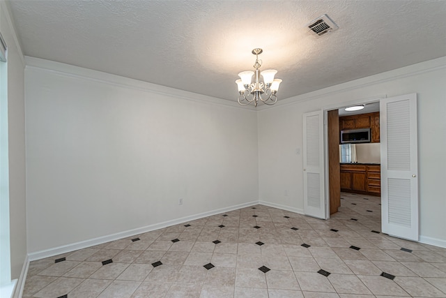 tiled empty room featuring a chandelier, a textured ceiling, and ornamental molding