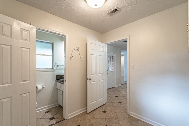 interior space featuring vanity, a textured ceiling, toilet, and tile patterned floors