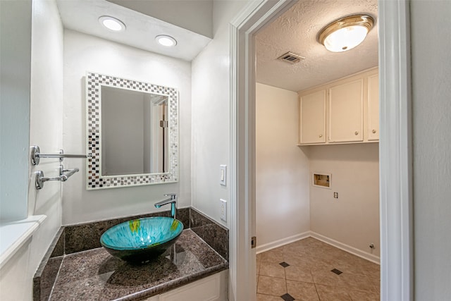 bathroom with tile patterned floors, sink, and a textured ceiling