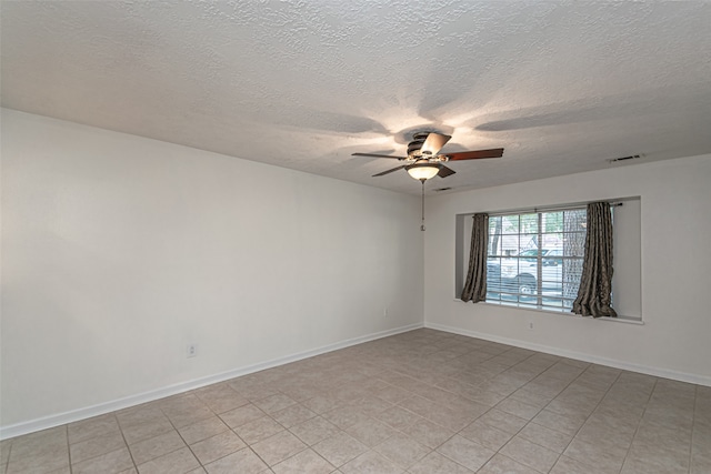 empty room with a textured ceiling, light tile patterned floors, and ceiling fan