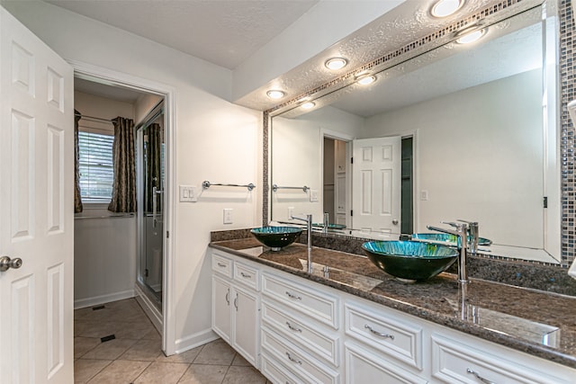 bathroom featuring double vanity, tile patterned flooring, and a textured ceiling