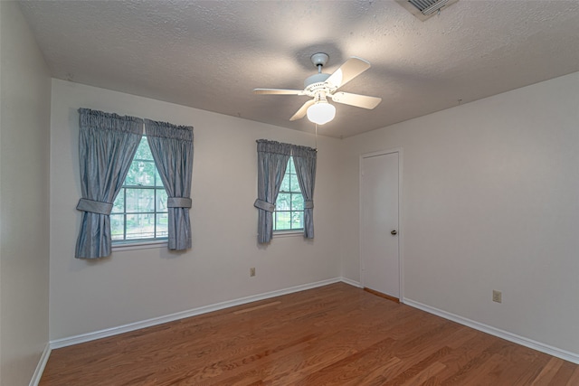 empty room with ceiling fan, a textured ceiling, and hardwood / wood-style flooring