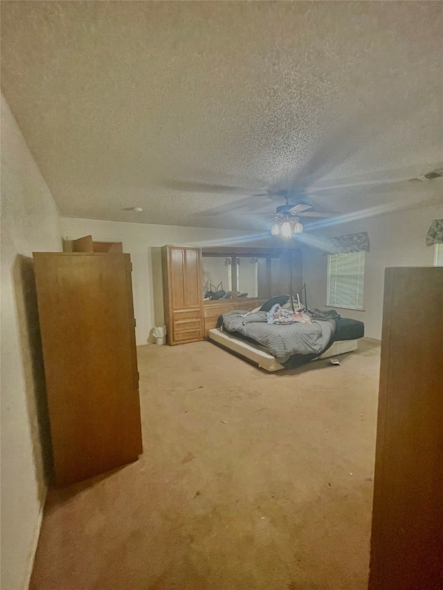 unfurnished bedroom featuring ceiling fan, a textured ceiling, and light carpet