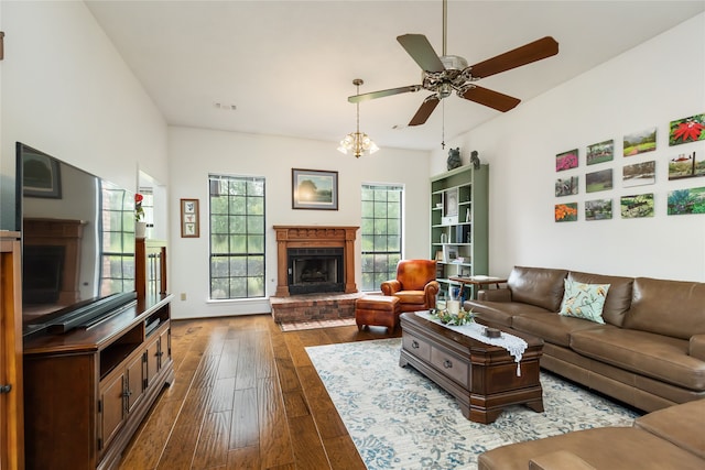 living room featuring a fireplace, hardwood / wood-style flooring, and ceiling fan with notable chandelier