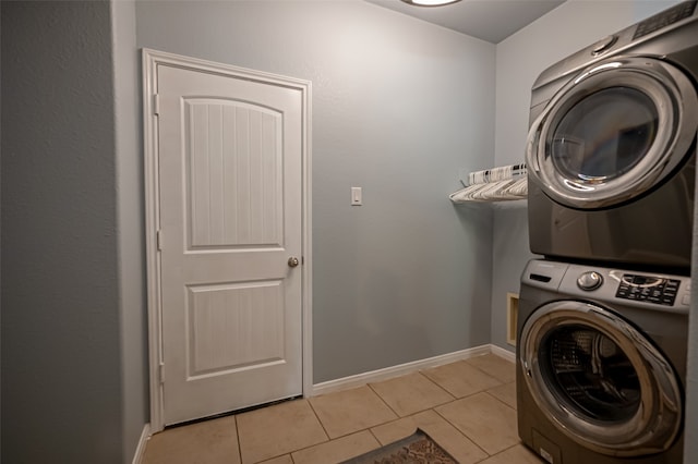 clothes washing area with light tile patterned floors and stacked washing maching and dryer