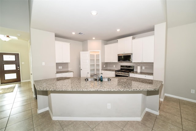 kitchen with white cabinetry, sink, stainless steel appliances, and a large island with sink