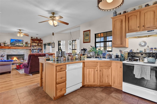 kitchen with tile patterned flooring, white appliances, ceiling fan, a stone fireplace, and sink