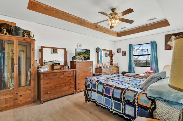 bedroom featuring a tray ceiling, light wood-type flooring, and ceiling fan