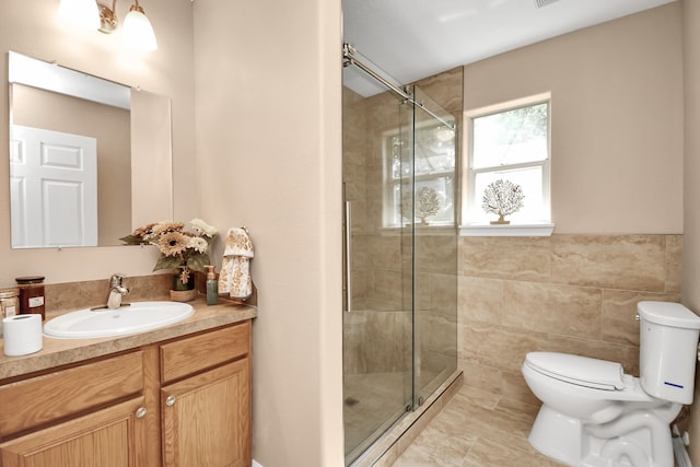 bathroom with a shower with shower door, tile patterned flooring, tile walls, toilet, and vanity