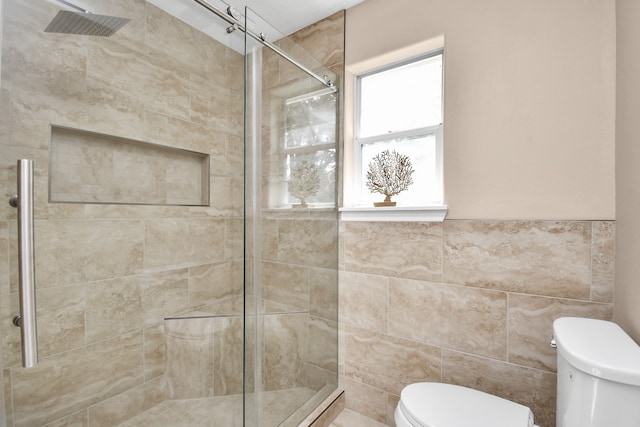 bathroom with a shower with door, tile walls, and toilet