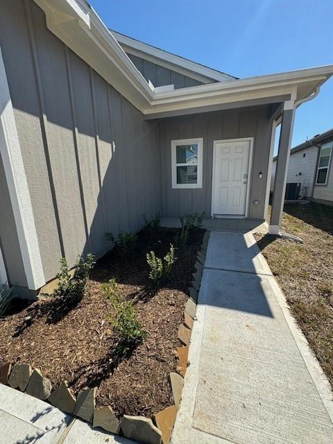 doorway to property with central AC unit and board and batten siding