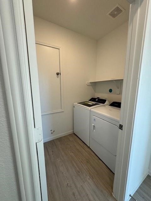 laundry area with washing machine and dryer and light wood-type flooring