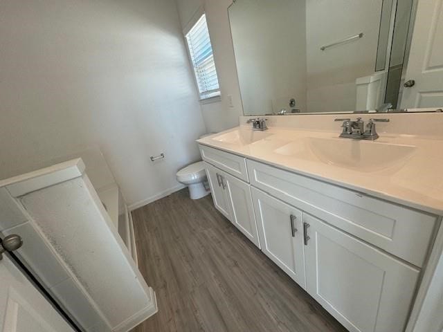 bathroom with vanity, toilet, hardwood / wood-style floors, and a bathtub