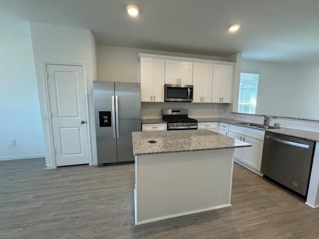 kitchen with appliances with stainless steel finishes, white cabinets, sink, and hardwood / wood-style flooring