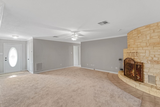 unfurnished living room featuring a stone fireplace, light colored carpet, crown molding, and ceiling fan