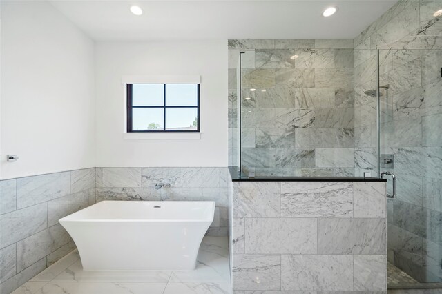 bathroom with tile walls and separate shower and tub