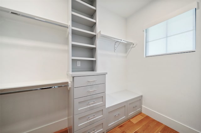 walk in closet with light hardwood / wood-style floors