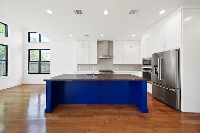 kitchen featuring appliances with stainless steel finishes, a center island with sink, white cabinetry, and a wealth of natural light