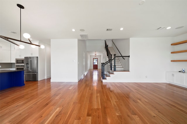 unfurnished living room featuring light wood-type flooring and an inviting chandelier