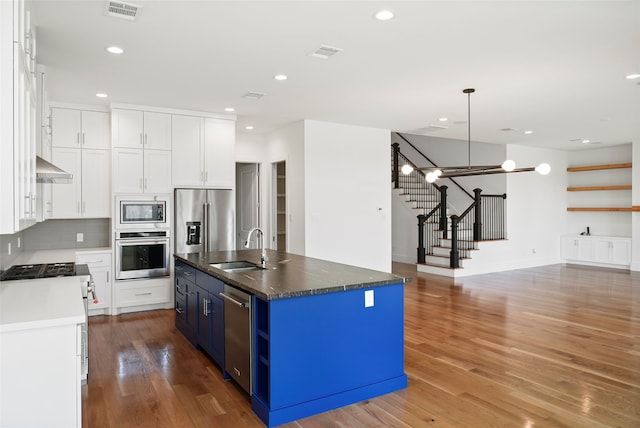 kitchen with blue cabinets, white cabinets, sink, a center island with sink, and stainless steel appliances