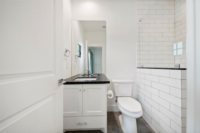 bathroom with vanity, tile walls, hardwood / wood-style floors, and toilet