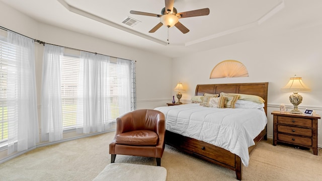 carpeted bedroom with a tray ceiling and ceiling fan