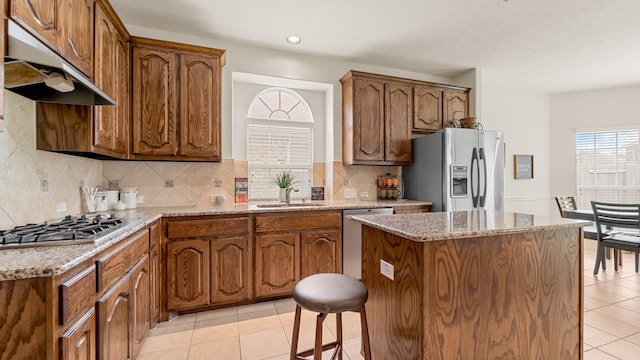 kitchen featuring sink, light tile patterned floors, a kitchen island, and appliances with stainless steel finishes