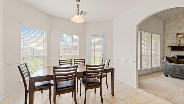 dining area featuring light colored carpet and a stone fireplace