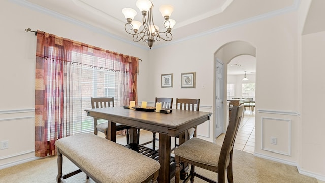 carpeted dining room featuring an inviting chandelier, crown molding, and a raised ceiling