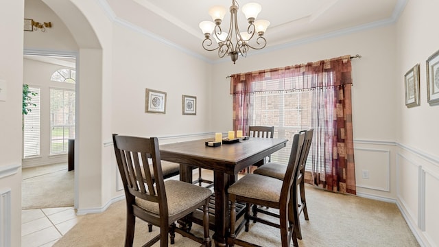 dining space with a chandelier, ornamental molding, a raised ceiling, and light carpet